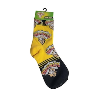 May include: Yellow and black crew socks featuring a repeating pattern of the Warheads logo and a cartoon character face. The packaging header includes the text Warheads, Crew Socks, and Fits Kids Ages 7-10. The socks have a black toe and heel section.