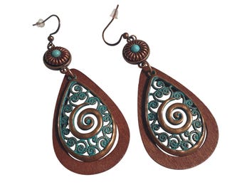 May include: A pair of copper-toned earrings with a teardrop shape. The earrings feature a turquoise accent and a teal filigree design with a spiral in the center. The earrings have a hook closure.