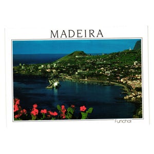 May include: A vintage postcard depicting a coastal view of Madeira, with the word "MADEIRA" at the top. The image shows a harbor with buildings, green hills, and red flowers in the foreground. The word "Funchal" is at the bottom.