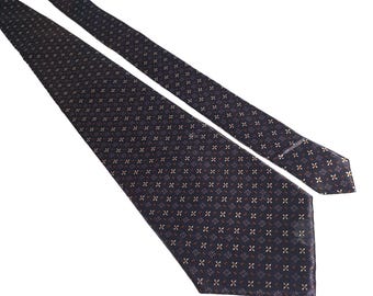 Puede incluir: Una corbata azul oscuro con un pequeño diseño geométrico blanco y naranja.