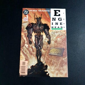 May include: Comic book cover featuring a muscular robot figure with a head shaped like a gear. The title "ENGINEHEAD" is displayed vertically. The cover includes the DC Comics logo and the text "FIRST GEAR JUNE 04".