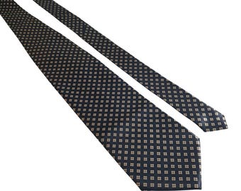 May include: A dark blue tie with a small, white and gold geometric pattern.