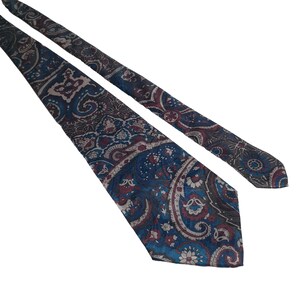 May include: A paisley patterned tie with a blue, gray, and burgundy color scheme.