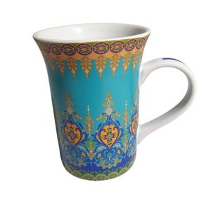 May include: A tall ceramic mug with a white interior and handle. The exterior features a vibrant turquoise base color adorned with intricate, symmetrical patterns in shades of orange, yellow, green, and dark blue, arranged in repeating motifs.