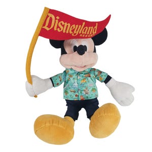 May include: A plush Mickey Mouse toy wearing a blue and green Hawaiian shirt with a Disneyland Resort logo on it. Mickey is holding a red flag with the Disneyland Resort logo in yellow lettering.