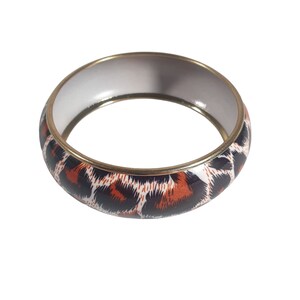 Può includere: Un braccialetto dorato con sfondo bianco e un design a stampa leopardata marrone e nero.