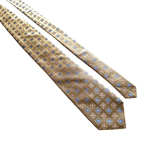 Puede incluir: Una corbata dorada con un patrón geométrico azul y rojo.