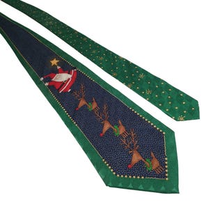 May include: A Christmas-themed necktie with a navy blue center featuring Santa Claus and reindeer. The tie has a green border and a green patterned section with gold stars. A festive accessory for the holiday season.