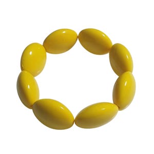 Peut inclure: Un bracelet composé de onze perles ovales jaunes brillantes. Les perles sont enfilées ensemble pour former une forme circulaire. Le bracelet est posé sur un fond blanc.