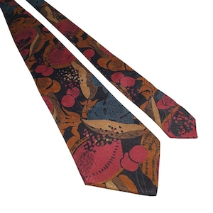 May include: A patterned tie with a dark background and a design of red, brown, and blue abstract shapes. The tie is made of a smooth fabric, suitable for formal or business wear.