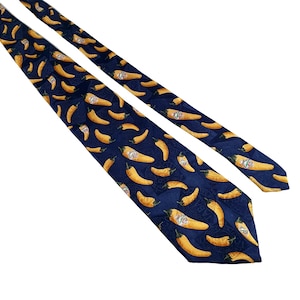 Può includere: Una cravatta di seta blu scuro con un motivo ripetitivo di peperoncini gialli. I peperoncini hanno un'etichetta rossa e bianca.