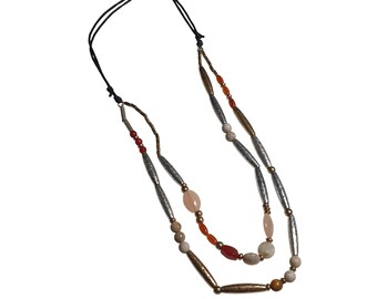 May include: A layered necklace with a black cord and various beads. The necklace features silver, gold, and bronze-colored metal beads, along with orange, pink, and beige-colored stone beads. The necklace is designed with two strands.