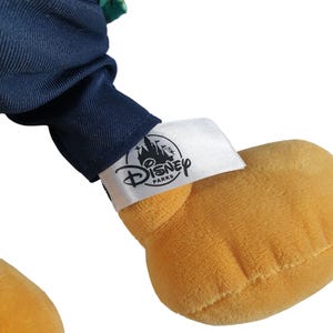 May include: A plush toy with a blue and green outfit and a white tag that says "Disney Parks".