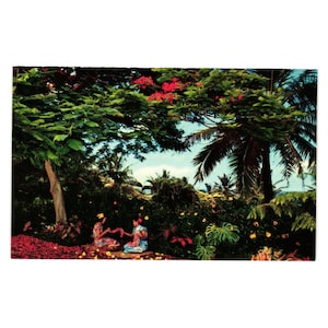 May include: Two people are sitting under a tree with pink flowers, making a lei out of flowers. The scene is tropical with palm trees and lush greenery.