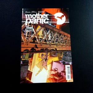 May include: A comic book cover for "Mother Panic" featuring a cityscape with a bridge and a figure in a costume. The title is in large white letters, with a bat symbol in a circle. The color scheme is orange, yellow, and black.