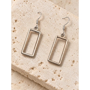 May include: A pair of silver-toned metal earrings featuring an open rectangular frame design. Each earring hangs from a simple curved ear wire hook, showcasing a clean, geometric silhouette with a smooth, polished finish throughout.