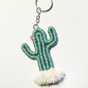 May include: A green and white crocheted cactus keychain with a pink flower.