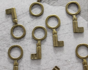 May include: A collection of antique-style brass skeleton keys with ornate keyholes. The keys are scattered on a light gray textured surface.
