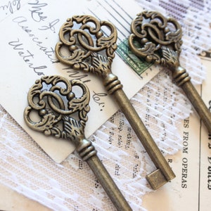 May include: Three ornate antique-style skeleton keys with intricate designs. The keys are made of brass and have a vintage look.