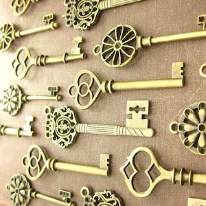 Könnte beinhalten: Eine Sammlung von antiken Skelettschlüsseln in verschiedenen verzierten Designs, darunter Blumen-, Kronen- und Herzmotive. Die Schlüssel sind aus goldfarbenem Metall gefertigt und haben eine patinierte Oberfläche.