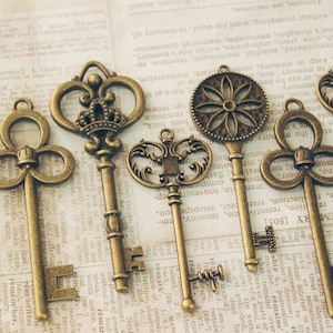 May include: A collection of six antique-style keys with ornate designs. The keys are made of metal and have a bronze finish. They are arranged on a piece of paper with text.