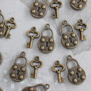 May include: Assortment of antique gold-toned key charms and lock charms. The charms feature intricate details and a vintage aesthetic.