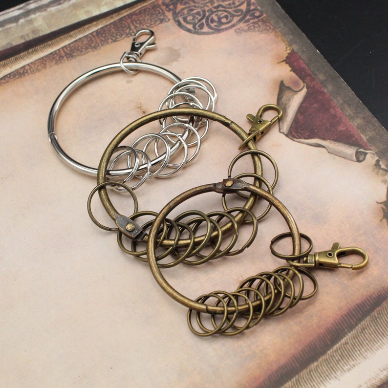 K&ouml;nnte beinhalten: Ein Satz Schl&uuml;sselanh&auml;nger mit mehreren silbernen und goldenen Ringen. Die Schl&uuml;sselanh&auml;nger sind miteinander verbunden und haben einen silbernen Verschluss.