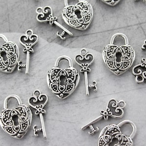 May include: A collection of silver-toned heart-shaped lock and key charms. The charms feature intricate designs and are perfect for adding a touch of vintage charm to jewelry or crafts.
