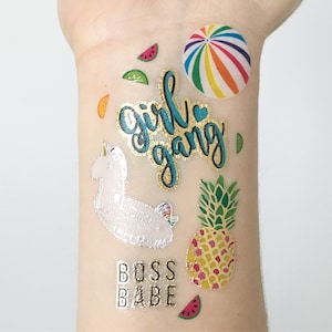 May include: A set of temporary tattoos featuring a unicorn, a pineapple, a watermelon, a beach ball, and the text "Girl Gang" and "Boss Babe".