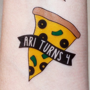 May include: A yellow and brown pizza slice with green and black toppings. A black ribbon with white text reads "ARI TURNS 4".