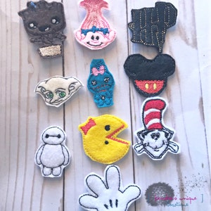 May include: A collection of felt character patches, including Groot, Poppy, Dobby, a blue monster, Mickey Mouse, Pac-Man, Cat in the Hat, Baymax, a Harry Potter lightning bolt, and a white gloved hand. Each patch is outlined in black.