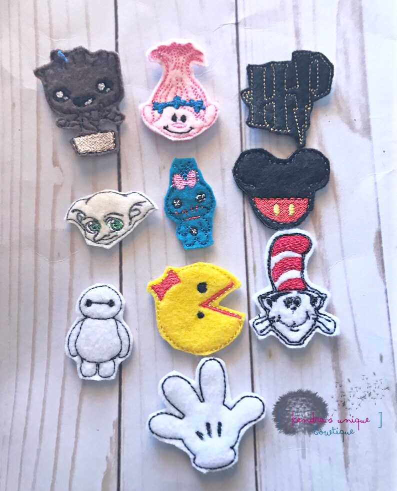 May include: A collection of felt character patches, including Groot, Poppy, Dobby, a blue monster, Mickey Mouse, Pac-Man, Cat in the Hat, Baymax, a Harry Potter lightning bolt, and a white gloved hand. Each patch is outlined in black.