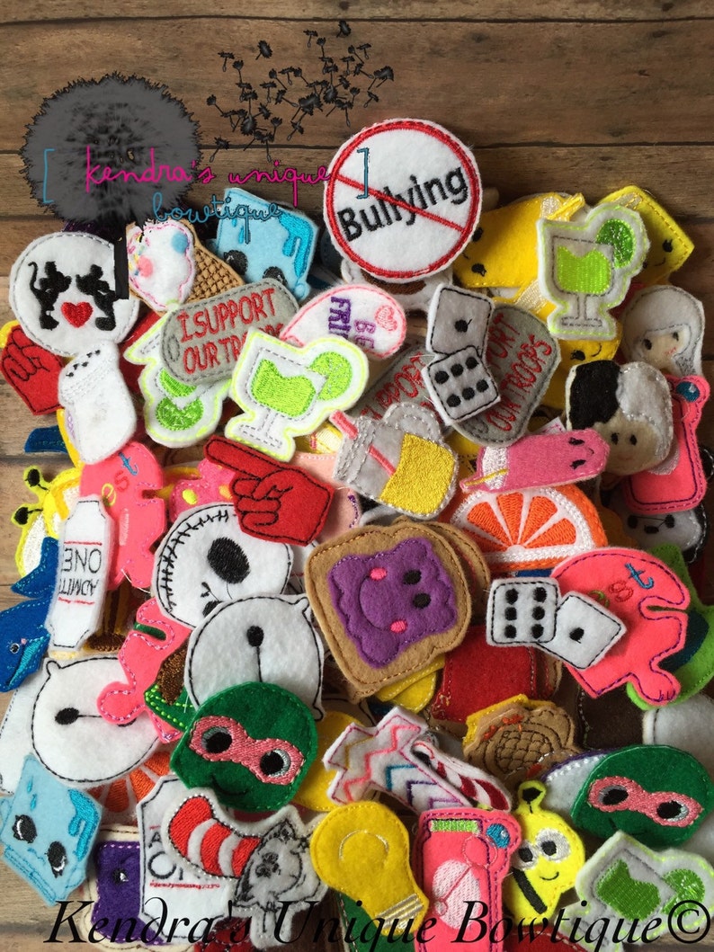 May include: A collection of colorful felt appliques in various shapes, including a stop sign with "Bullying" crossed out, dice, and cartoon characters. The appliques are scattered on a wooden surface.