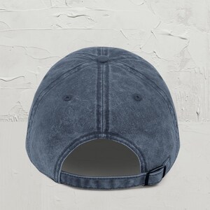 May include: A dark blue denim baseball cap with a classic design. The cap has a structured crown and a curved brim. The back of the cap has an adjustable strap.