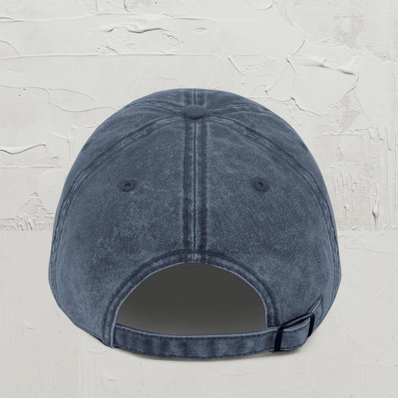 May include: A dark blue denim baseball cap with a classic design. The cap has a structured crown and a curved brim. The back of the cap has an adjustable strap.
