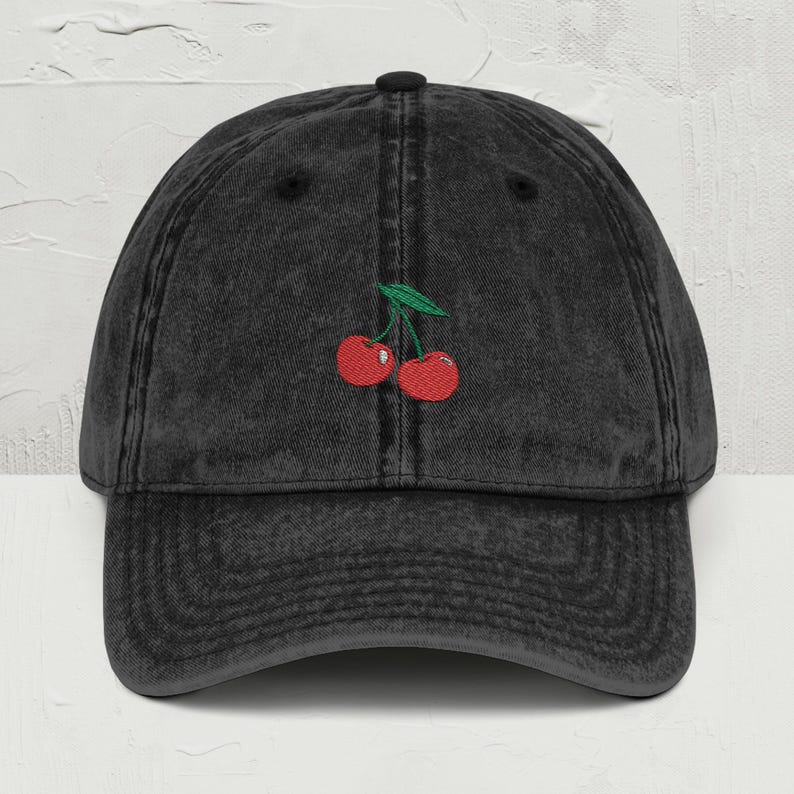 May include: A black vintage washed denim baseball cap with a red cherry embroidery.