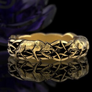 May include: A gold-colored ring featuring a repeating pattern of wolves and interwoven geometric shapes. The wolves are depicted in a running or attacking pose, with their mouths open. The ring's design is detailed and intricate, with a polished finish.