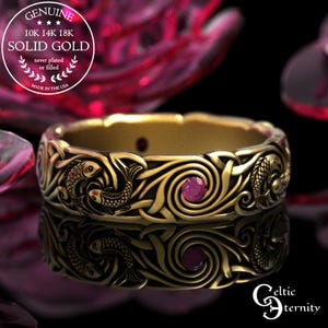 May include: A gold ring with a Celtic knot design, featuring fish and swirling patterns. The ring has small, round, pink gemstones. The text "GENUINE SOLID GOLD" is visible. The ring is made in the USA.