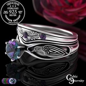 Könnte beinhalten: Ein silbernes Ring-Set mit einem großen, mehrfarbigen Edelstein und aufwendigen keltisch inspirierten Designs. Das Set beinhaltet ein Band mit Blatt- und Edelsteinakzenten und einen Ring mit einem Vogelmotiv. Die Ringe sind mit "925 Silver" und "Made in the USA" gekennzeichnet.