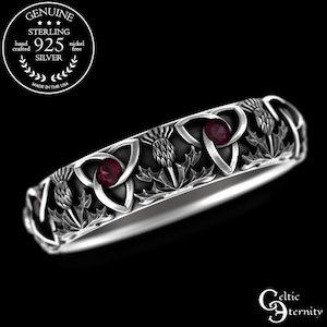 May include: Sterling silver ring featuring a Celtic knot design and three red gemstones. The ring is adorned with thistle flowers.