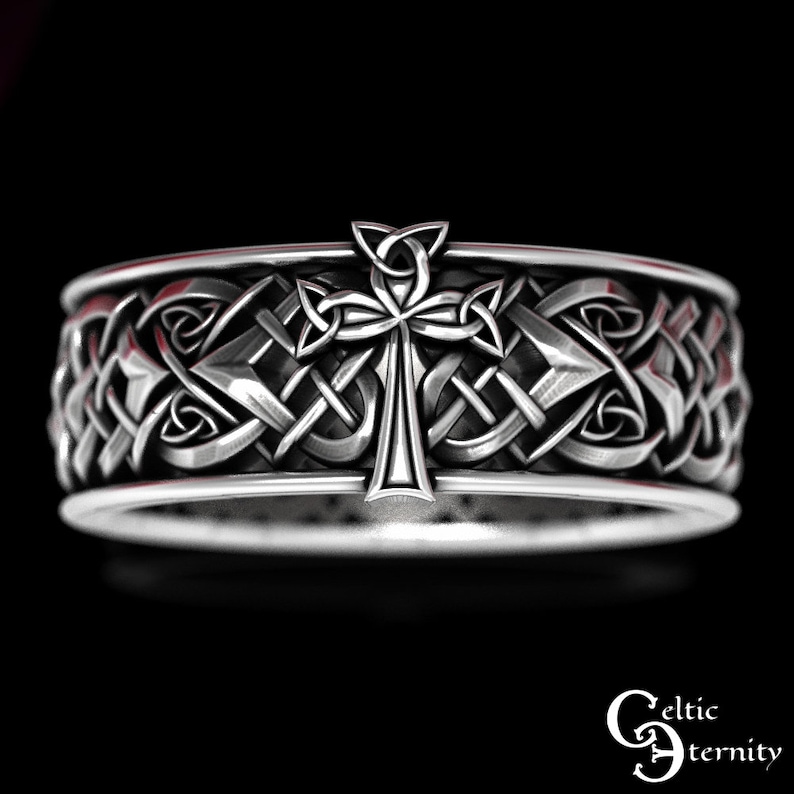 May include: Silver Celtic knot ring with a cross design. The ring is intricately detailed and features a Celtic knot pattern.