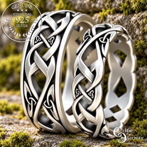 Könnte beinhalten: Zwei Ringe aus Sterlingsilber mit einem komplizierten, durchbrochenen keltischen Knotenmuster. Das Metall hat eine polierte Oberfläche mit abgedunkelten vertieften Bereichen. Ein kreisförmiges Emblem links zeigt Genuine Sterling 925 Silver hand crafted nickel free.