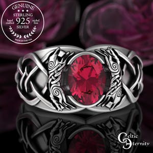 May include: A sterling silver ring with a large oval ruby gemstone. The ring features a Celtic knot design with intricate detailing and the text "GENUINE STERLING 925 SILVER" in a circular emblem. Made in the USA.