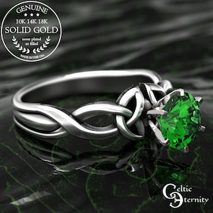 May include: A silver-colored ring with a Celtic knot design and a large, round, bright green gemstone. The ring is labeled "Genuine Solid Gold" and "Made in the USA". The text "Celtic Eternity" is also visible.
