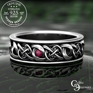 May include: A sterling silver ring with a Celtic knot design and a red gemstone. The ring is marked "925 Silver" and "Made in the USA". The ring is nickel free and hand crafted.