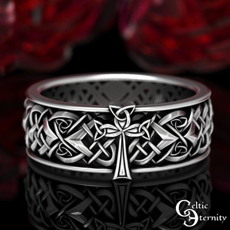 May include: A silver Celtic knot ring with a cross design. The ring is intricately detailed and has a polished finish.