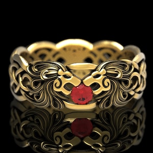 May include: A gold ring with a red gemstone set in the center. The ring features two lion heads facing each other, with intricate details and a Celtic knot design.
