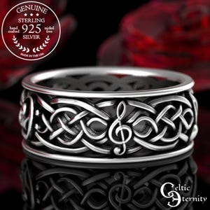 May include: Sterling silver Celtic knot ring with a treble clef design. The ring is hand-crafted and nickel-free. "GENUINE STERLING 925 SILVER" and "MADE IN THE USA" are inscribed on the band.