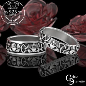 Könnte beinhalten: Zwei silberne keltische Knotenringe mit einem Claddagh-Design. Die Ringe sind aus Sterlingsilber gefertigt und werden in den USA handgefertigt. Die Ringe zeigen ein Herz, Hände und eine Krone.