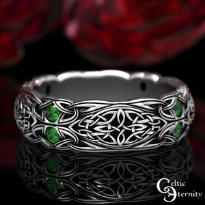 May include: A silver Celtic knot ring with green gemstones. The ring is intricately designed with a Celtic knot pattern and features four green gemstones.